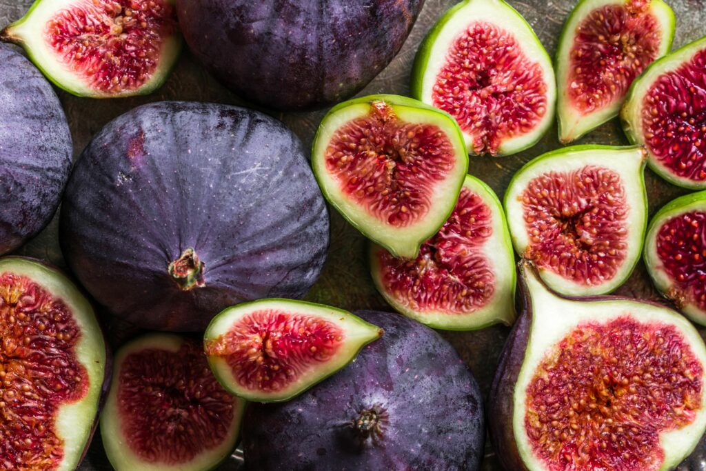 Fresh figs, whole and halved, showing their rich purple skins and vibrant red interiors.