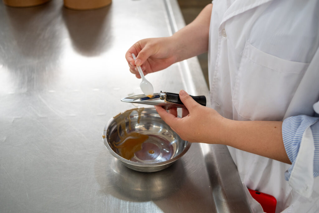 Technician measuring a liquid food ingredient with a refractometer