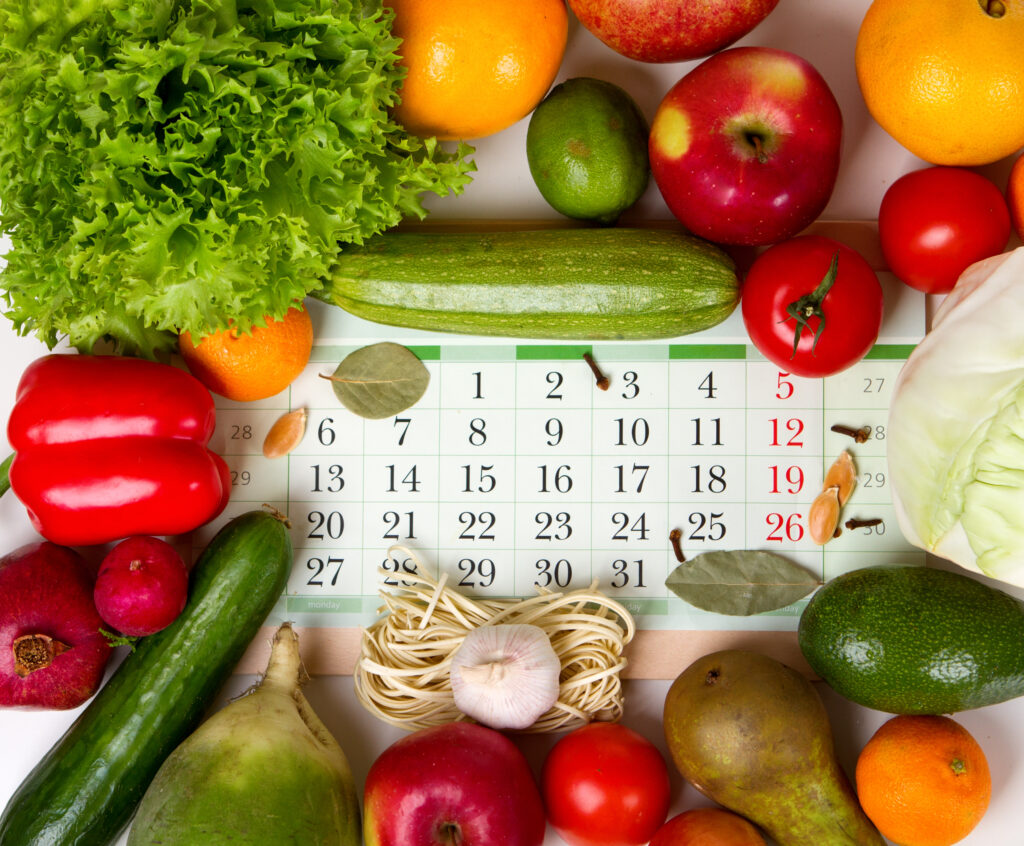 Calendar surrounded by fresh fruits and vegetables representing seasonal planning