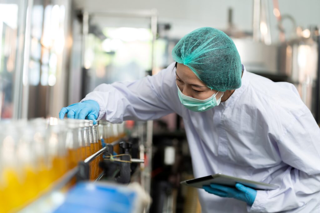Quality-control worker inspecting bottled juice on a production line